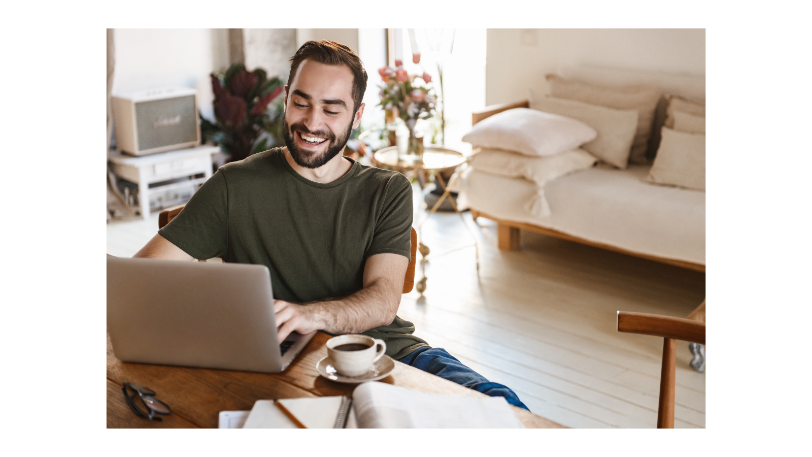 Man sitting at a table with coffee typing on his laptop