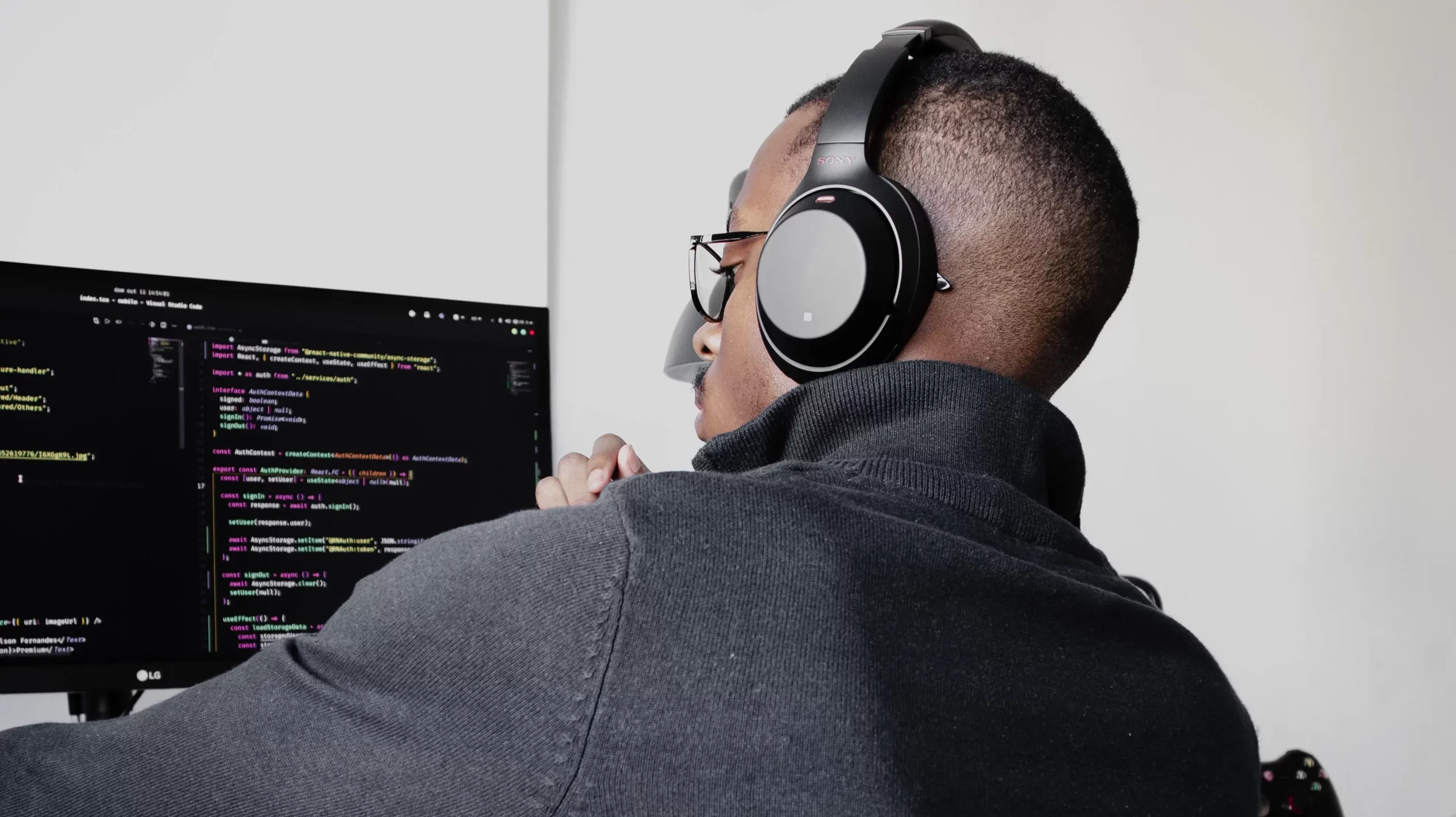 Man coding at his desk with headphones on