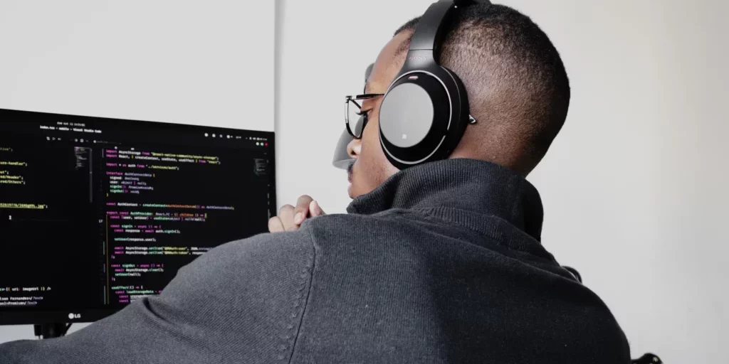 Man coding at his desk with headphones on